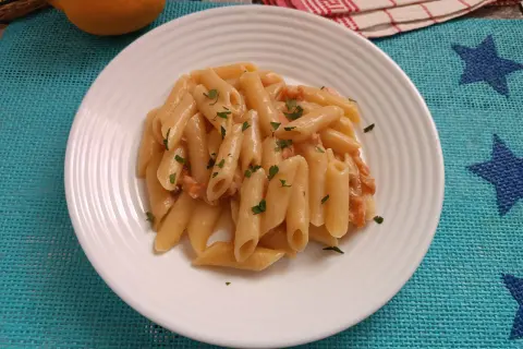 Piatto di pasta al salmone senza panna, guarnita con prezzemolo fresco. Un'opzione leggera e gustosa.