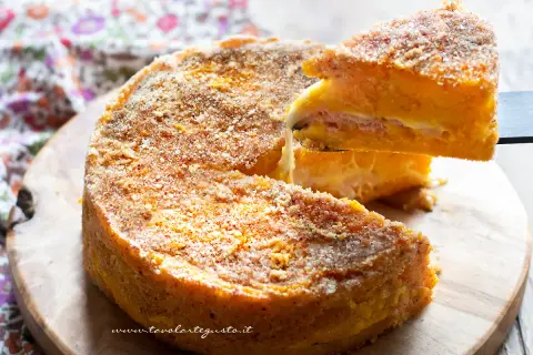 Una fetta di zucca al forno, soffice e dorata, con strati di formaggio e prosciutto, pronta per essere gustata.