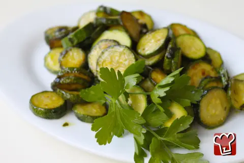 Zucchine alla poverella, fette di zucchine saltate in padella con aglio e prezzemolo fresco, un contorno semplice e gustoso.