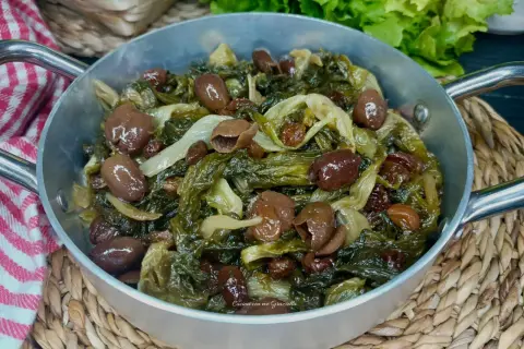 Scarola in padella con olive e uvetta, un contorno saporito e colorato, pronto per essere gustato.