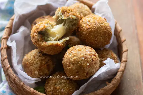 Croccanti polpette di carciofi con cuore filante di formaggio, servite in un cestino di vimini.