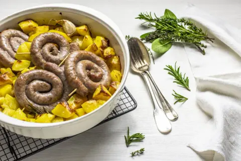 Salsiccia e patate al forno, un piatto rustico e saporito, con erbe aromatiche e aglio.