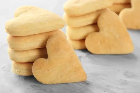 Biscotti a forma di cuore, impilati su una superficie grigia. Deliziosi biscotti senza uova, perfetti per ogni occasione.