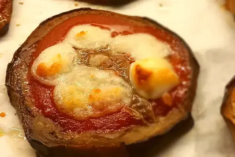 Pizzette di melanzane con pomodoro e mozzarella filante, un antipasto gustoso e leggero.