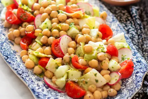 Insalata di ceci fresca e colorata con pomodorini, cetrioli e ravanelli, condita con erbe aromatiche.