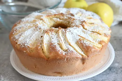 Ciambella alle mele soffice e profumata, cosparsa di zucchero a velo, con mele a vista.