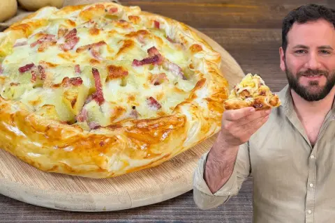Una golosa torta salata patate e speck, con un uomo che ne mostra una fetta invitante.