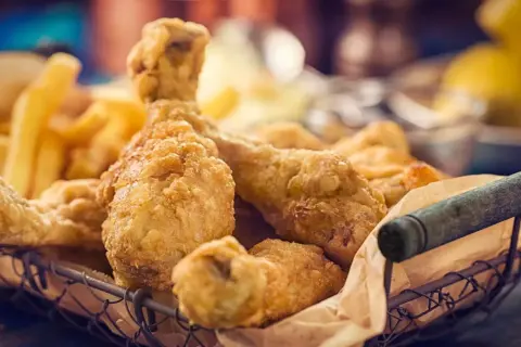 Cesto pieno di croccante petto di pollo impanato e patatine fritte dorate.