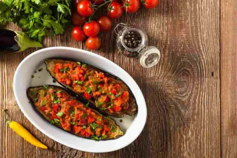 Melanzane a barchetta ripiene, pronte per essere gustate. Ingredienti freschi e un tocco di peperoncino giallo.