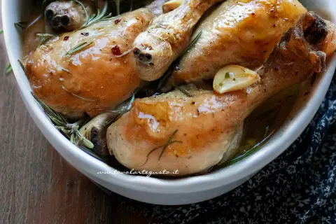 Succulente sovracosce di pollo al forno, dorate e profumate con aglio e rosmarino, servite in una ciotola bianca.