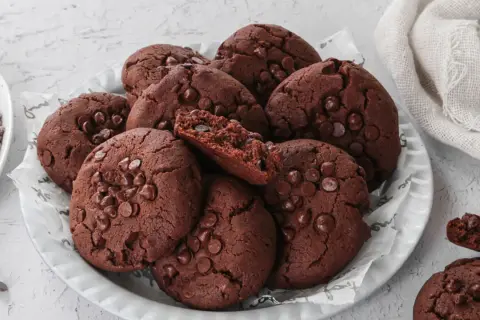 Un mucchio di deliziosi biscotti al cioccolato, perfetti per chi cerca biscotti senza burro. Alcuni sono interi, altri spezzati, rivelando un interno morbido e ricco.