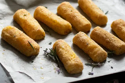 Crocchette di patate al forno dorate e croccanti, pronte per essere gustate. Profumate con rosmarino fresco.