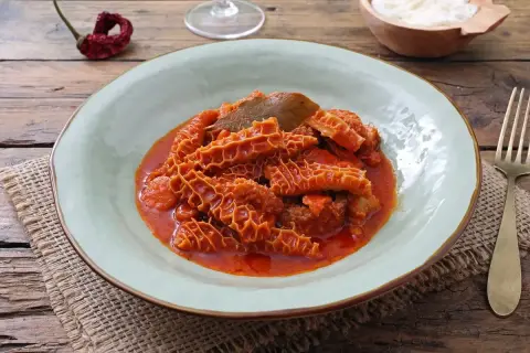Un piatto fumante di trippa alla fiorentina, con la sua consistenza unica e il sugo rosso invitante, pronto per essere gustato.