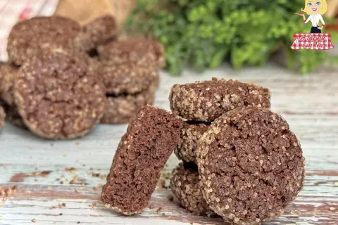 Biscotti al cioccolato rustici, ricoperti di zucchero grezzo, su un tavolo di legno. Uno spezzato rivela la consistenza friabile.
