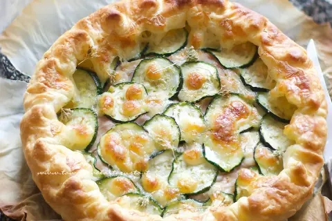 Torta salata con zucchine, formaggio filante e crosta dorata, pronta per essere gustata.