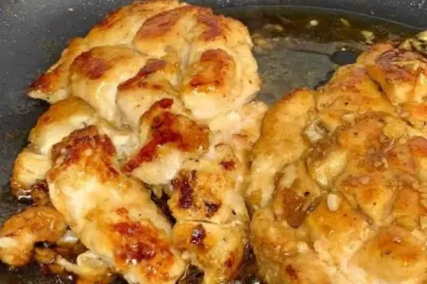 Succulento pollo in padella, dorato e saporito, con pezzetti di aglio che aggiungono un tocco in più.