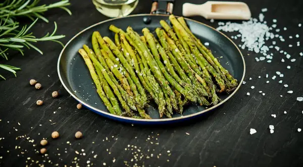 Asparagi in padella, conditi con sale e pepe, pronti per essere gustati.