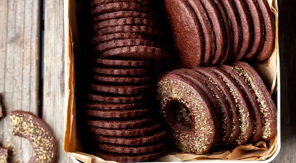 Una scatola piena di deliziosi biscotti al cacao, alcuni impilati in modo ordinato, altri con un bordo dorato croccante.