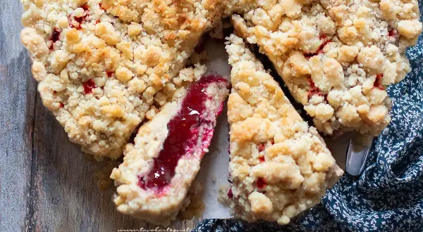 Una deliziosa sbriciolata alla marmellata, con la sua crosta dorata e il ripieno rosso brillante, pronta per essere gustata.
