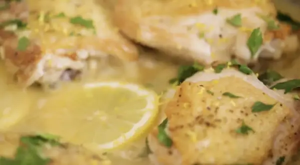 Succulento pollo al limone, dorato e profumato, con fette di limone e prezzemolo fresco.