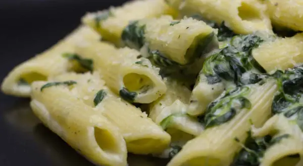 Penne cremose con spinaci freschi e parmigiano grattugiato, un piatto semplice e gustoso.