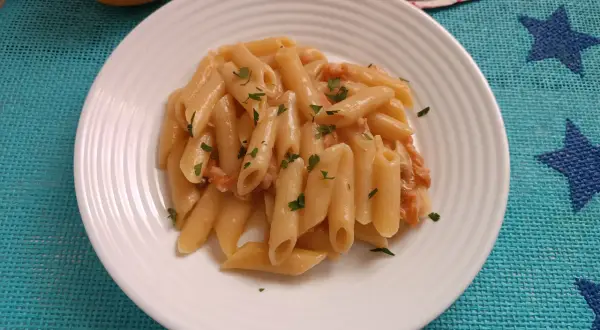 Piatto di pasta al salmone senza panna, guarnita con prezzemolo fresco. Un'opzione leggera e gustosa.