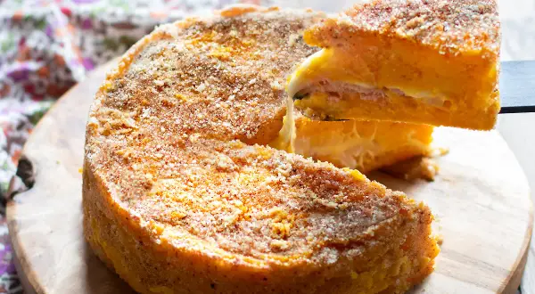 Una fetta di zucca al forno, soffice e dorata, con strati di formaggio e prosciutto, pronta per essere gustata.