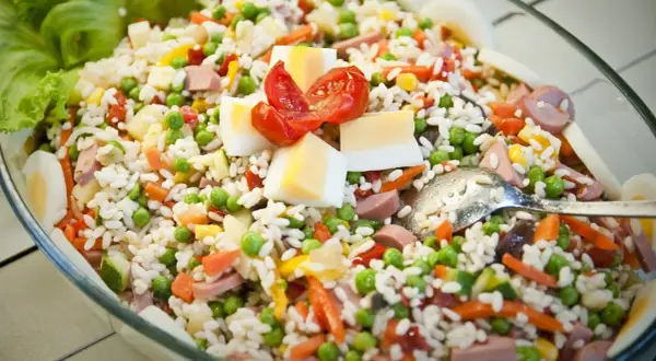 Insalata di riso ricca di ingredienti: piselli, carote, uova sode, pomodorini e salumi. Perfetta per un pasto fresco e completo.