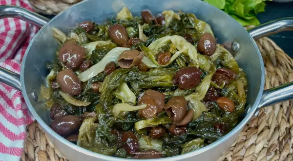 Scarola in padella con olive e uvetta, un contorno saporito e colorato, pronto per essere gustato.