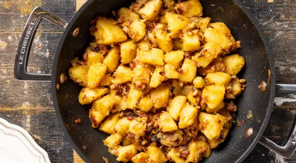 Patate in tecia dorate e croccanti, condite con pancetta e cipolla, pronte per essere gustate.