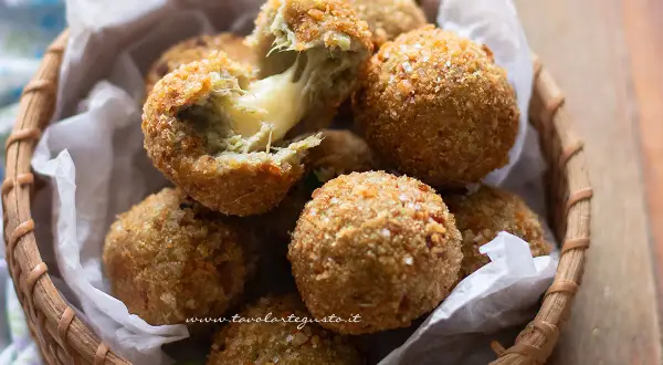 Croccanti polpette di carciofi con cuore filante di formaggio, servite in un cestino di vimini.