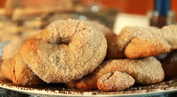 Ciambelline al vino dorate e cosparse di zucchero, un dolce profumato e croccante, perfetto per accompagnare un caffè.