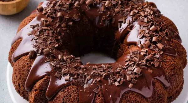Ciambellone al cioccolato con glassa lucida e riccioli di cioccolato fondente. Un dolce invitante e goloso.