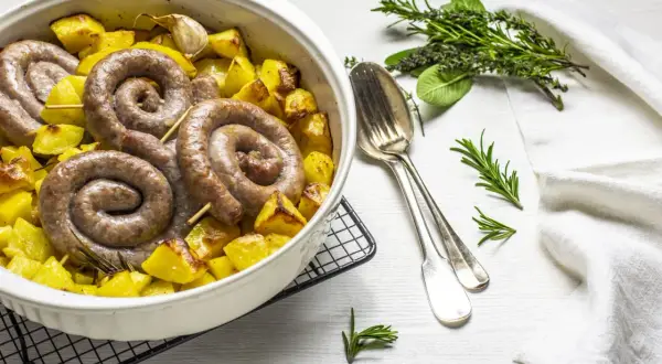 Salsiccia e patate al forno, un piatto rustico e saporito, con erbe aromatiche e aglio.