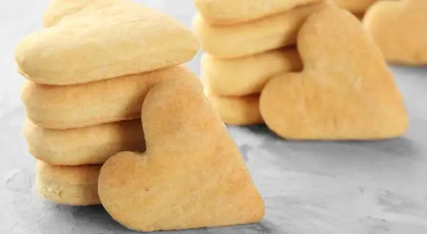 Biscotti a forma di cuore, impilati su una superficie grigia. Deliziosi biscotti senza uova, perfetti per ogni occasione.