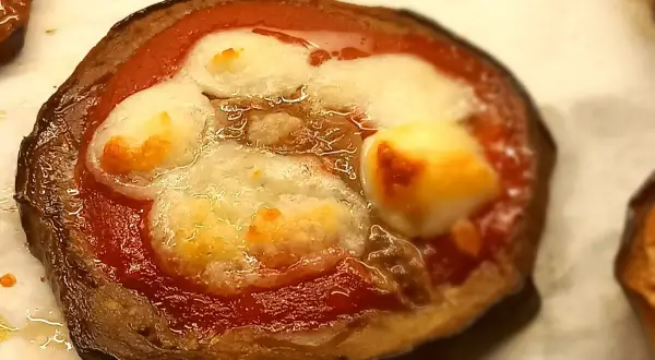 Pizzette di melanzane con pomodoro e mozzarella filante, un antipasto gustoso e leggero.