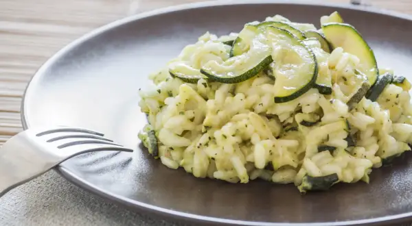 Un cremoso risotto con zucchine, guarnito con fette sottili di zucchine fresche, pronto per essere gustato.