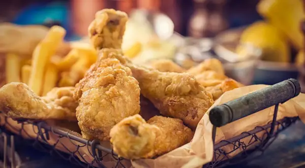 Cesto pieno di croccante petto di pollo impanato e patatine fritte dorate.