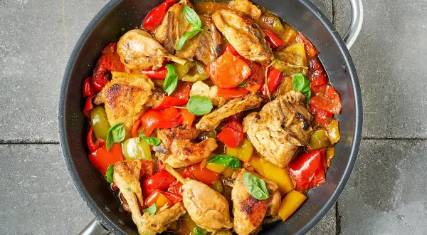 Pollo e peperoni in padella, un piatto colorato e saporito, con pezzi di pollo dorati e peperoni rossi e gialli cotti a puntino.
