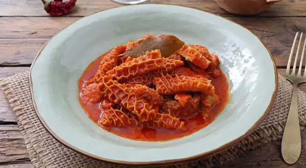 Un piatto fumante di trippa alla fiorentina, con la sua consistenza unica e il sugo rosso invitante, pronto per essere gustato.