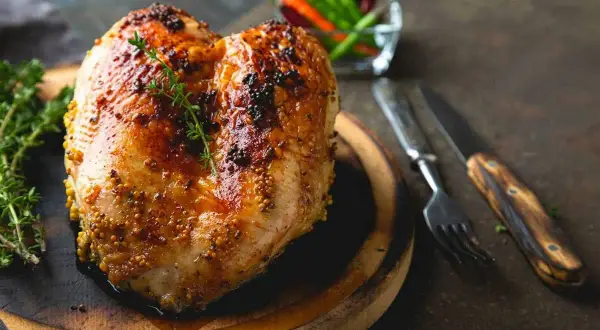 Petto di pollo al forno dorato e succulento, condito con senape e erbe aromatiche, pronto per essere gustato.