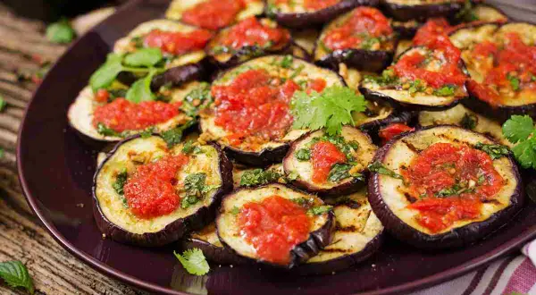 Fette di melanzane grigliate condite con salsa di pomodoro e basilico, un classico piatto di melanzane alla pizzaiola.