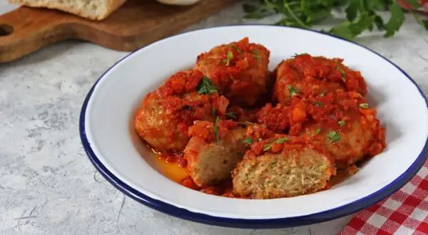 Polpette di pane succulente in salsa di pomodoro, guarnite con prezzemolo fresco. Un piatto casalingo che sa di tradizione.