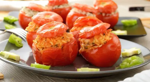 Pomodori ripieni di riso, un piatto colorato e saporito, con peperoni verdi e zucchine a guarnire.