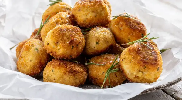 Un mucchio invitante di polpette in bianco, dorate e croccanti, guarnite con rosmarino fresco e sale grosso.