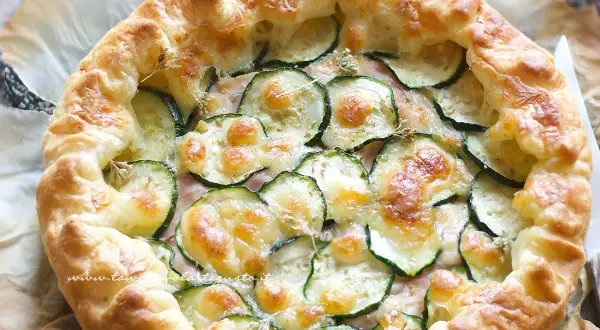 Torta salata con zucchine, formaggio filante e crosta dorata, pronta per essere gustata.