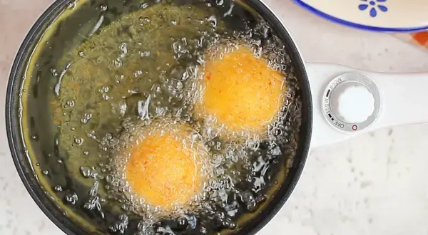 Arancini di riso dorati friggono nell'olio bollente, creando un profumo invitante.
