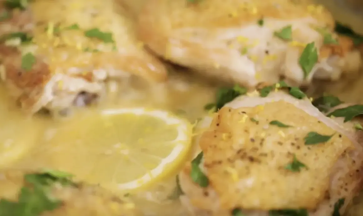 Succulento pollo al limone, dorato e profumato, con fette di limone e prezzemolo fresco.