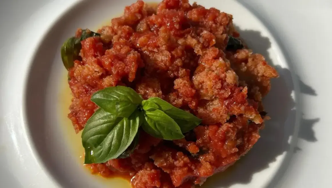 Piatto di pappa al pomodoro, un classico toscano, guarnito con foglie di basilico fresco.