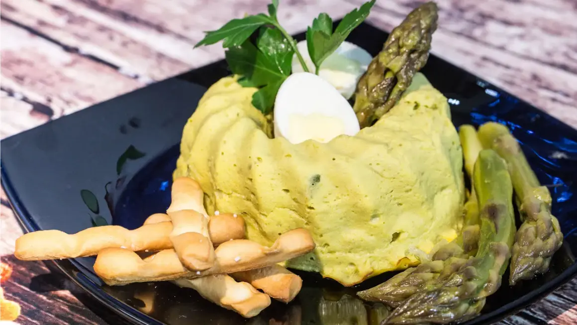 Delizioso flan di asparagi, guarnito con uovo sodo, asparagi freschi e grissini croccanti. Un piatto primaverile da gustare.